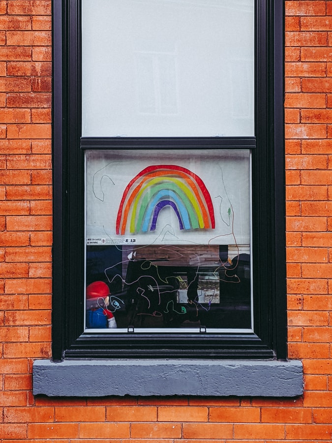Fotografía de una ventana con un marco color negro. La ventana tiene dibujado un arcoiris. 